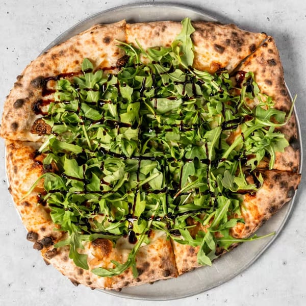 A Franco Martini Bar & Restaurant pizza, topped with fresh arugula and a balsamic glaze drizzle.