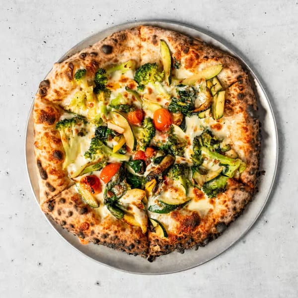 Franco Martini's Italian pizza, topped with broccoli, zucchini, cherry tomatoes, and melted cheese.
