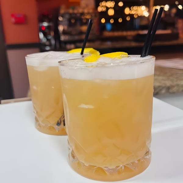 Two Franco Martini Bar & Restaurant cocktails with foam, lemon slices, and black straws.
