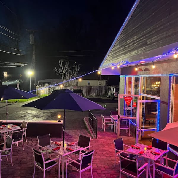Outdoor patio of Franco Martini Bar & Restaurant at night, with illuminated tables, umbrellas, and string lights.